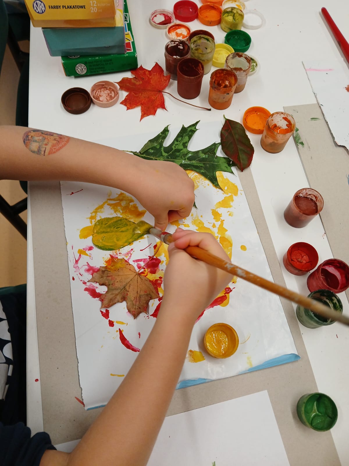 dziecko wykonuje pracę plastyczną z malowanych liści photo-2025-10-01-10-09-12.jpg